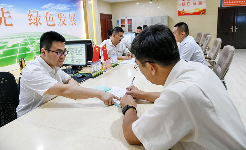 2019年7月16日,在内蒙古自治区自然资源厅的自然资源政务大厅内,办事员(左)为采矿企业办理相关审批手续。新华社记者 彭源 摄